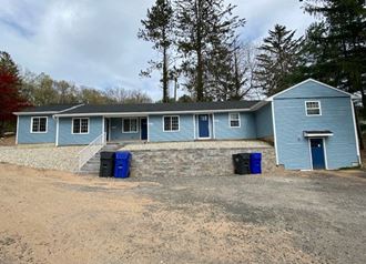 a blue house with blue trash cans in front of it