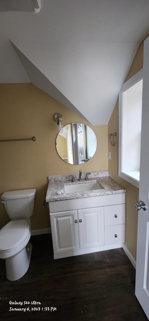 A bathroom with a toilet, sink and mirror.