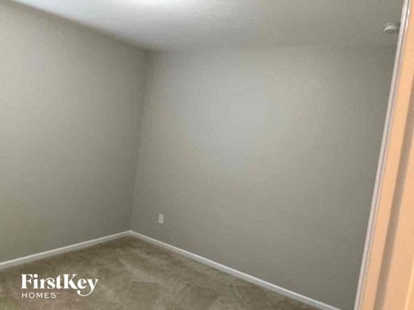 a empty room with a white wall and a brown floor