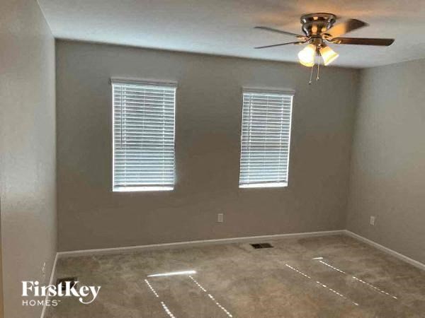 a empty room with a ceiling fan and three windows