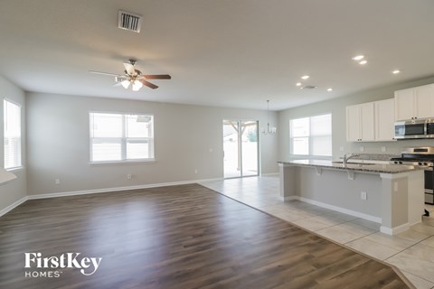 A spacious kitchen and living room with wooden floors and white walls.