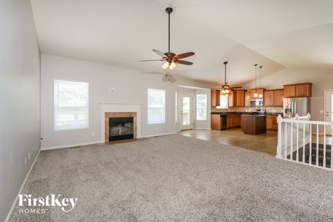 A spacious living room with a fireplace and a ceiling fan.