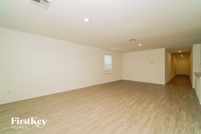 A spacious room with wooden flooring and white walls, with a doorway leading to another room.