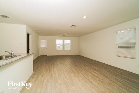 A spacious room with wooden flooring and a kitchen area with a sink.