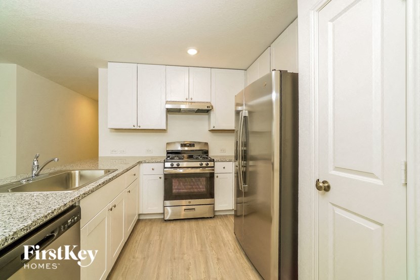 A kitchen with a refrigerator, sink, and stove.