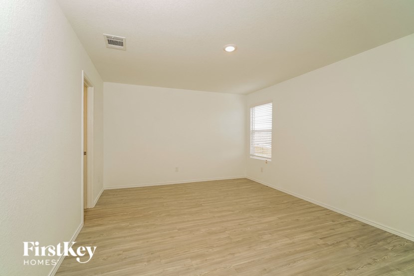 A room with wooden flooring and a window with blinds.