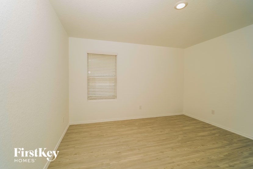 A room with wooden flooring and a window with blinds.