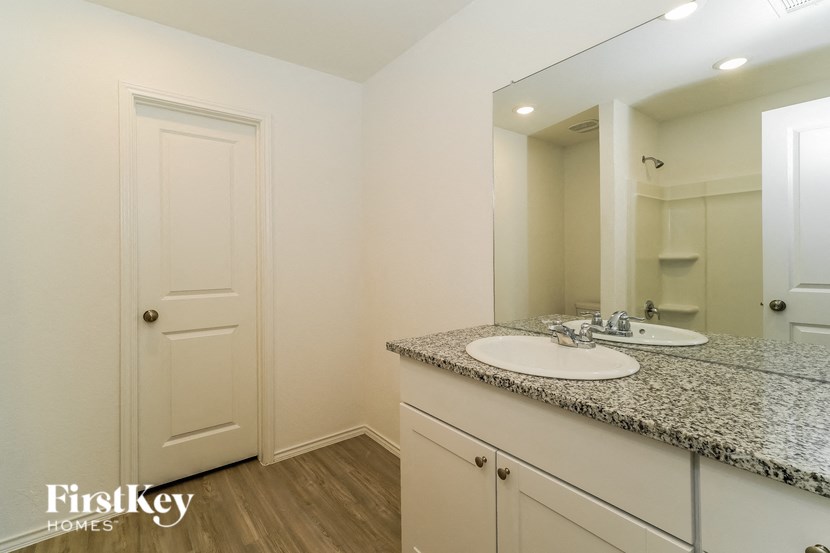 A bathroom with a granite countertop and a double sink vanity.