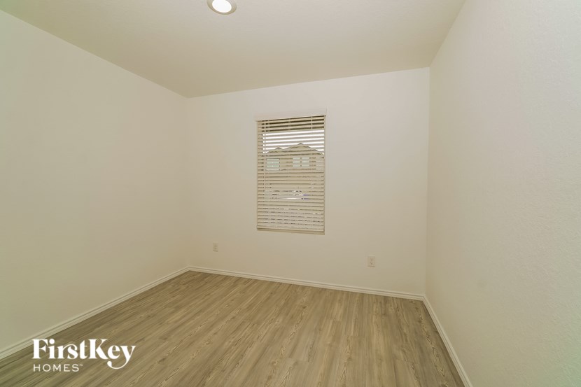 A room with wooden flooring and a window with blinds.