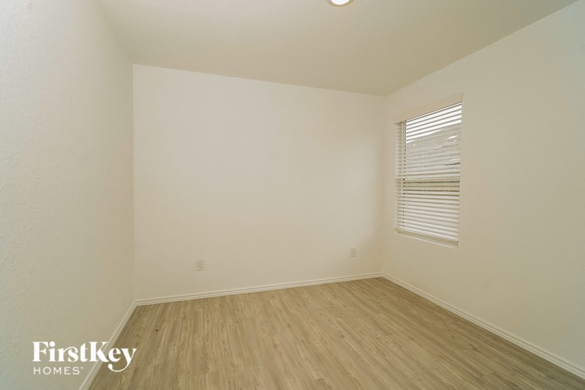 A room with wooden flooring and a window with blinds.