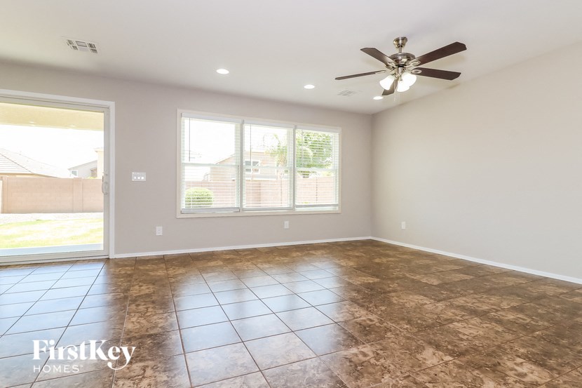 an empty living room with a ceiling fan and a window