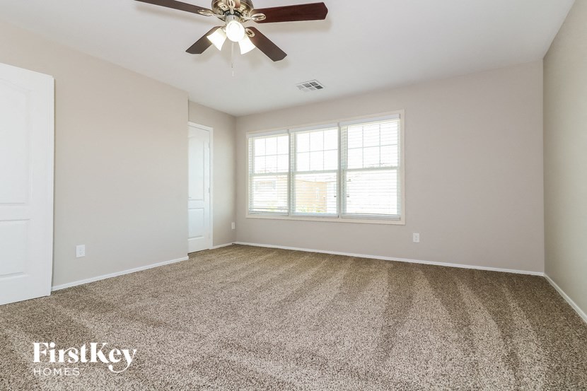 an empty living room with a ceiling fan and a window