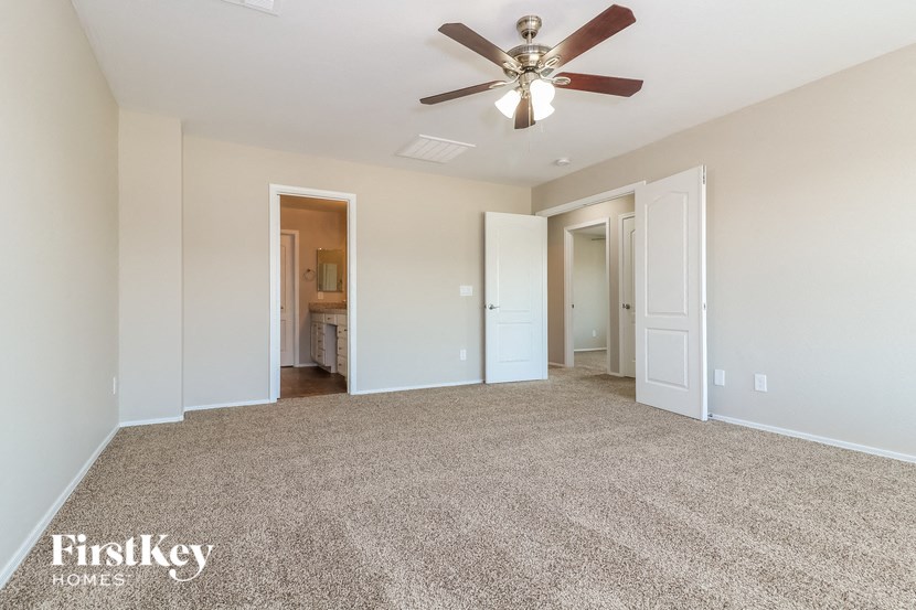an empty living room with a ceiling fan and white walls