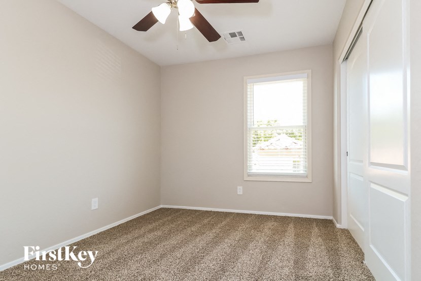 an empty room with a ceiling fan and a window