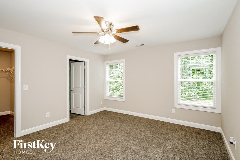 an empty bedroom with a ceiling fan and a door