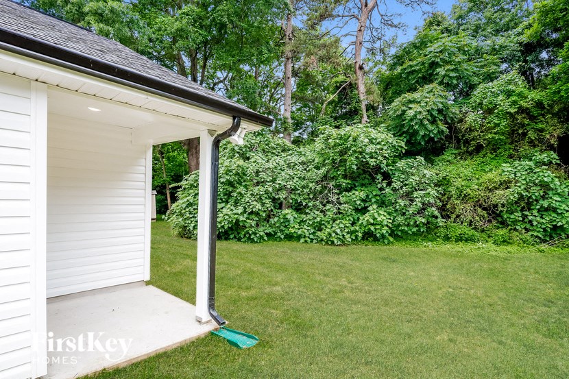 the backyard of a white house with a lawn and trees