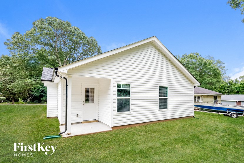 a small white house with a boat in the background