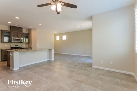 A spacious kitchen and living room with a ceiling fan and lighting.