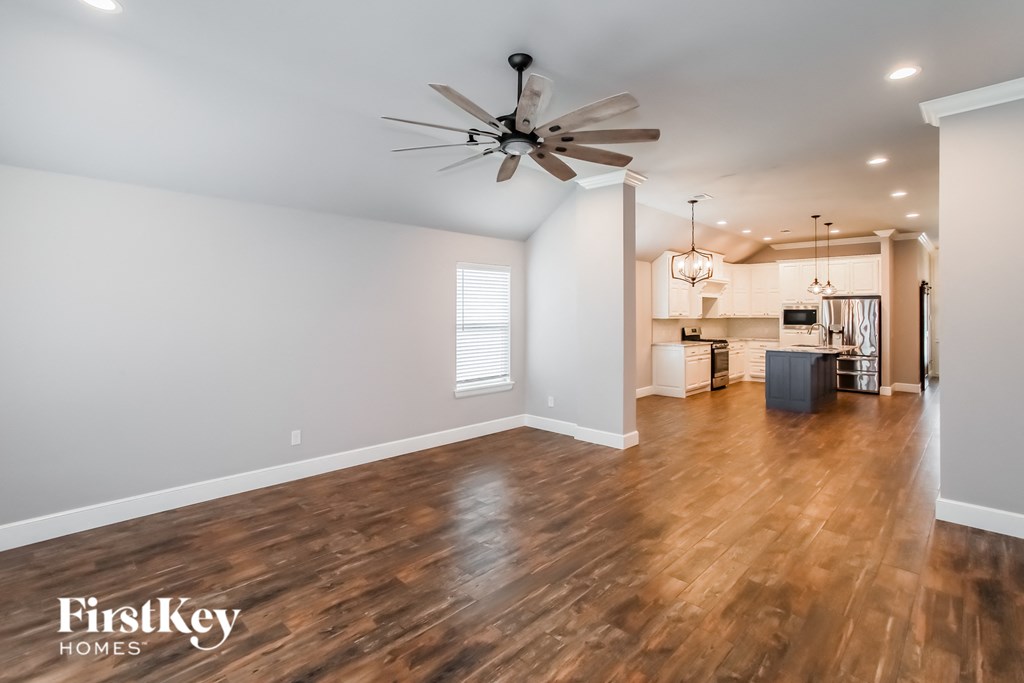the living room and kitchen with hardwood flooring and a ceiling fan