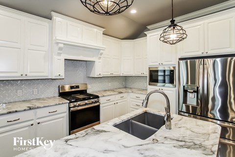 a white kitchen with marble counter tops and stainless steel appliances