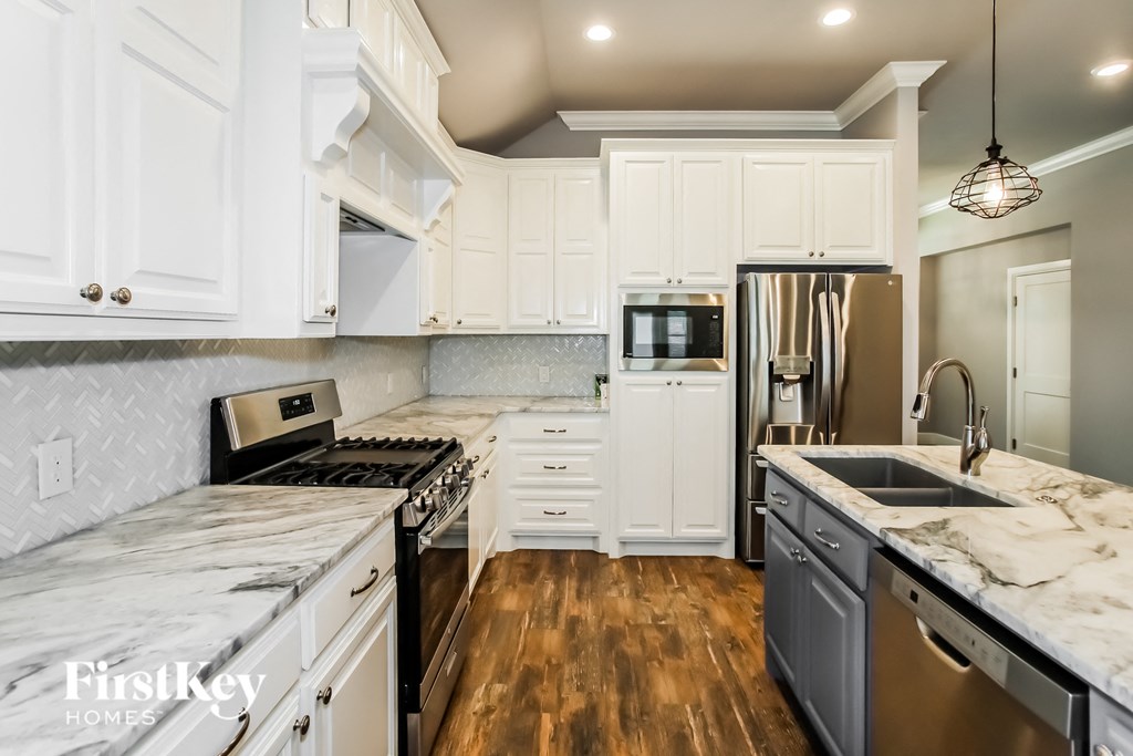 a white kitchen with marble counter tops and stainless steel appliances