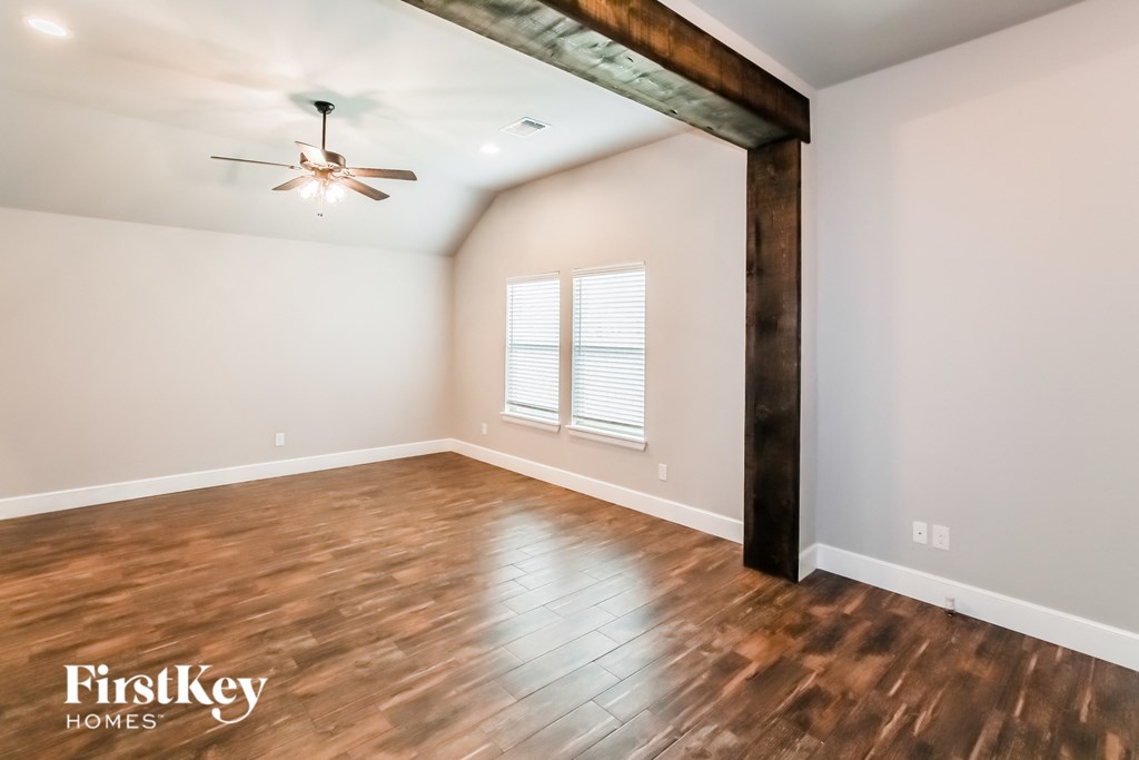 an empty room with wood floors and a ceiling fan
