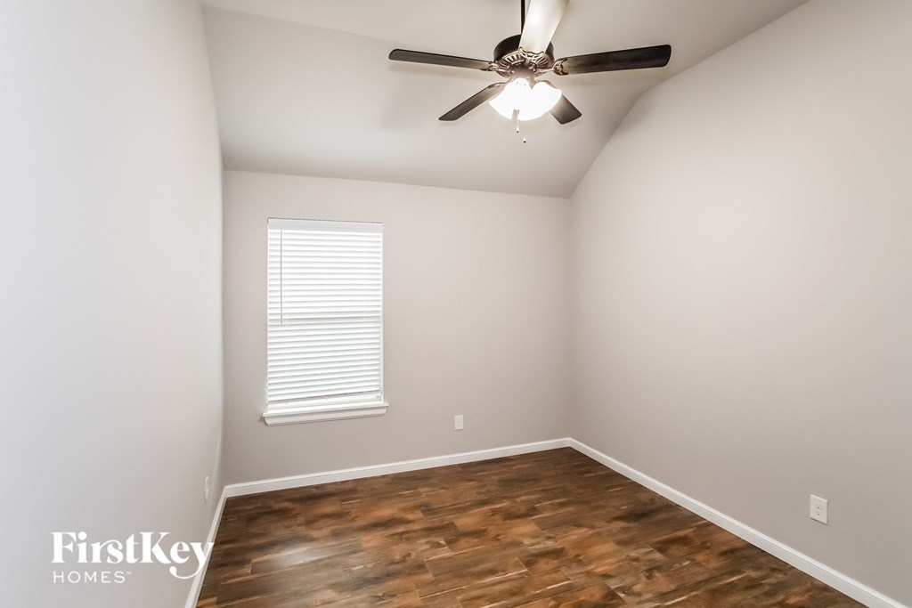 an empty room with a ceiling fan and a window