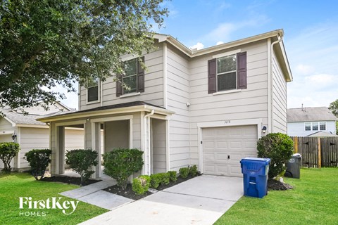 a white house with a blue trash can in front of it