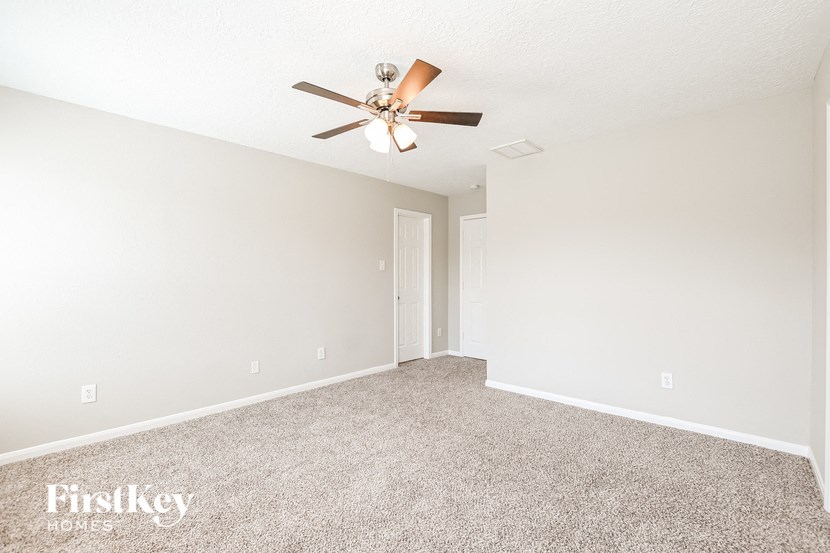 the spacious living room with ceiling fan and carpet