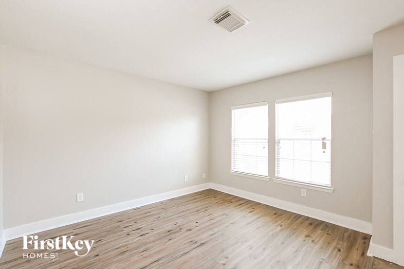 the spacious living room with hardwood flooring and two windows