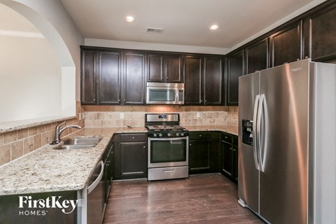 A kitchen with a stainless steel refrigerator and wooden cabinets.