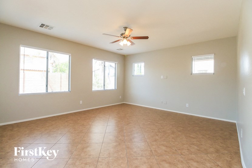 an empty living room with a ceiling fan and a tiled floor