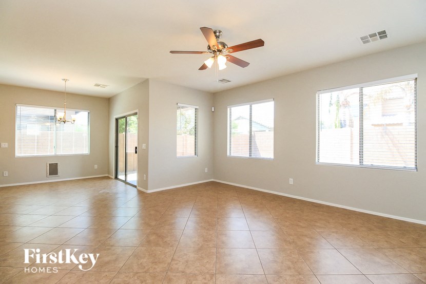 an empty living room with a ceiling fan and windows