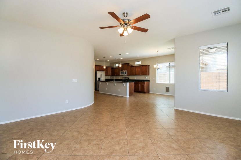 an empty living room and kitchen with a ceiling fan