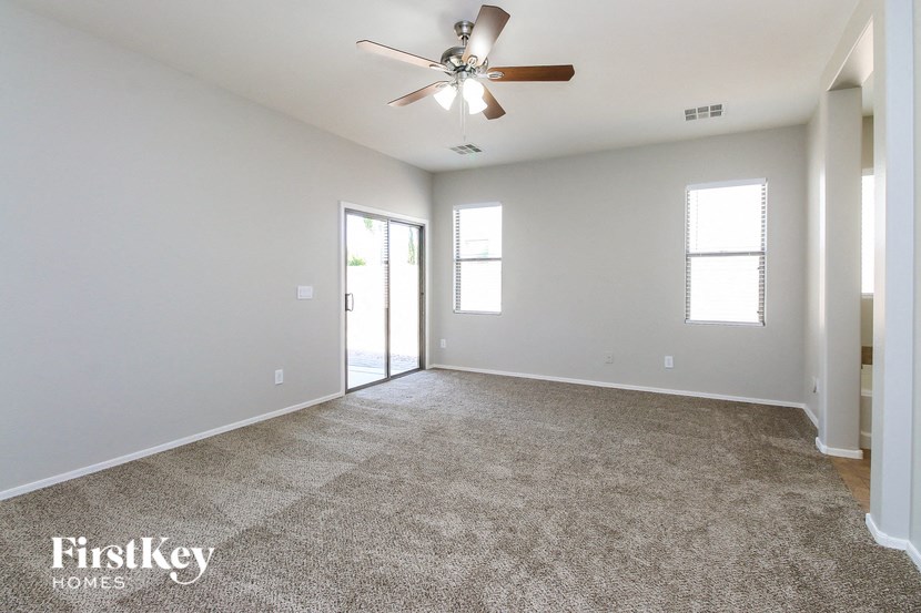 an empty living room with carpet and a ceiling fan