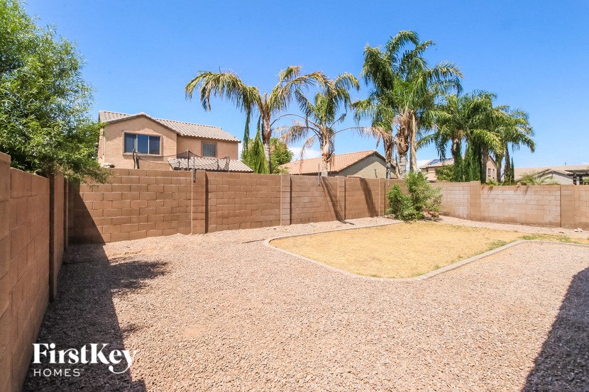 a backyard with a retaining wall and palm trees