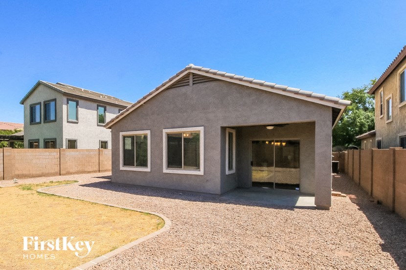 a small gray house with a driveway and a fence