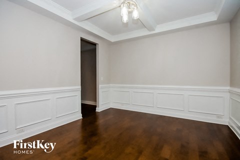 a living room with white walls and wooden floors and a doorway