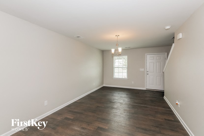 an empty living room with a white wall and wood floors