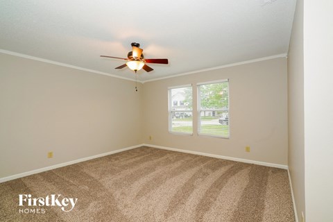 the master bedroom has a carpeted floor and a ceiling fan