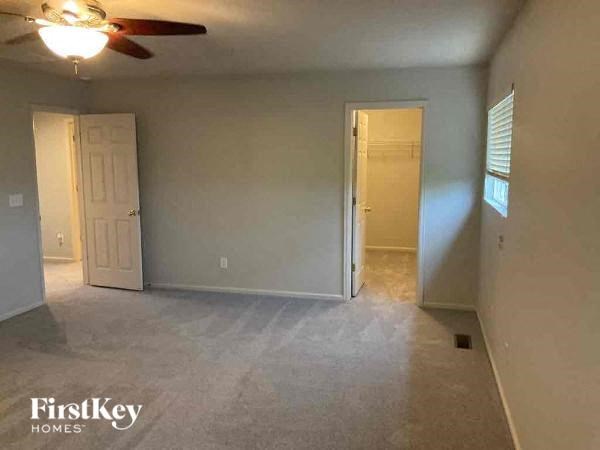 an empty living room with a ceiling fan and a door