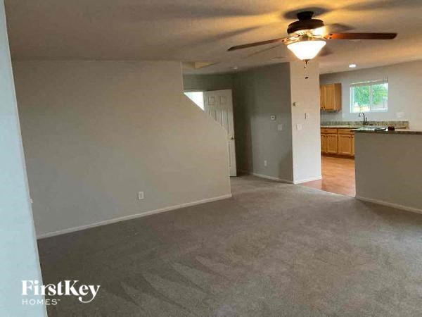 an empty living room and kitchen with a ceiling fan