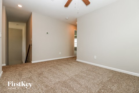 a empty living room with carpet and a ceiling fan