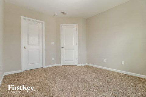a bedroom with two doors and a carpeted floor