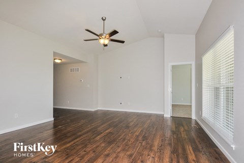 the spacious living room with wood flooring and a ceiling fan