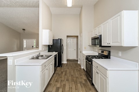 A kitchen with white cabinets and a black fridge.