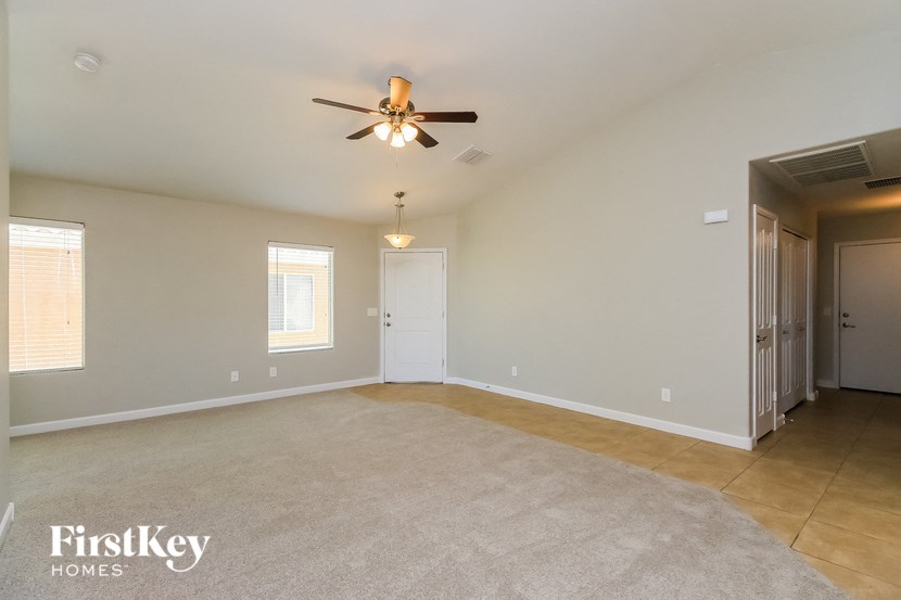 an empty living room with a ceiling fan