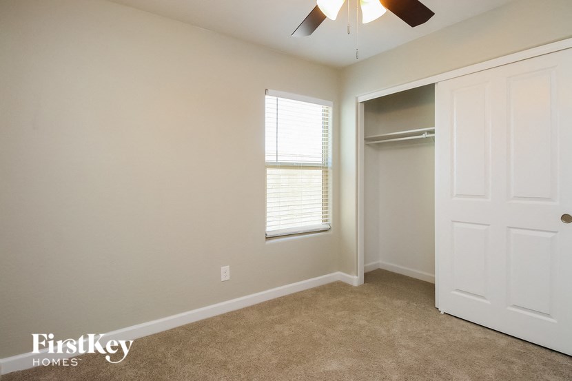 a bedroom with a closet and a window and a ceiling fan