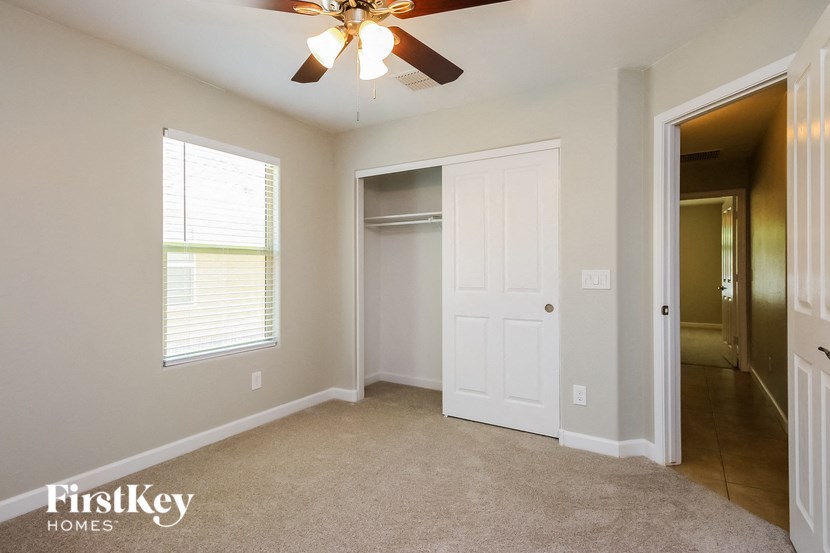 an empty bedroom with a ceiling fan and a closet