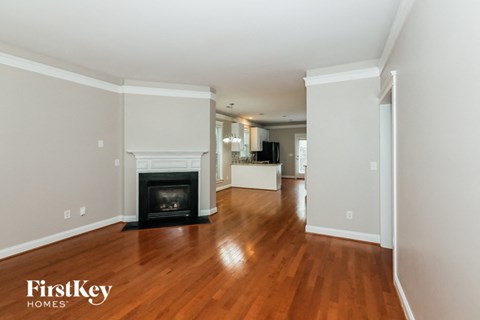 A living room with a fireplace and wooden floors.